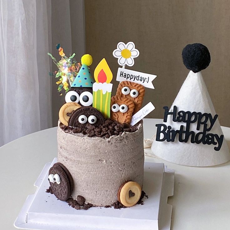 a birthday cake with decorations on it sitting on top of a white table next to a paper hat