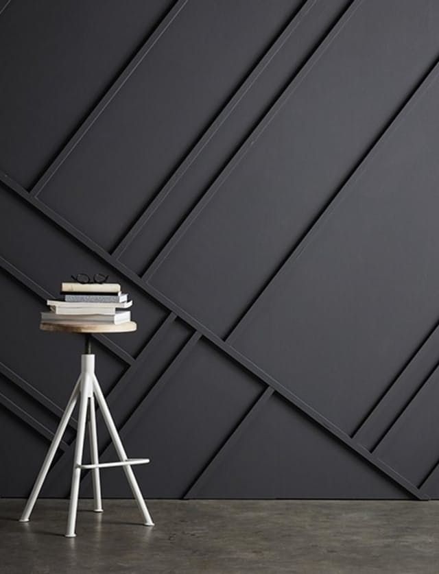 a white chair sitting next to a wooden table on top of a cement floor in front of a black wall