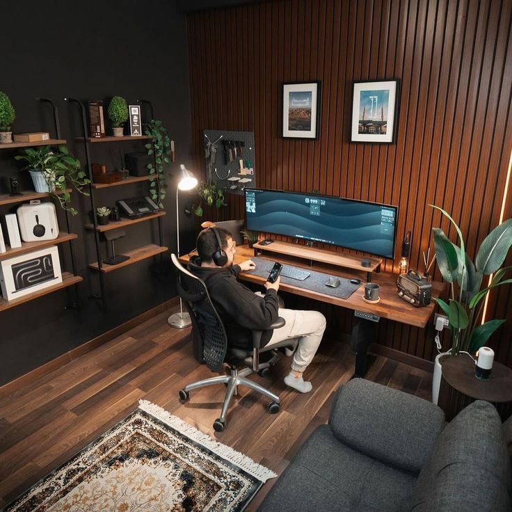 a person sitting at a desk in front of a computer on top of a wooden floor