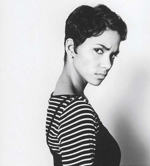 a black and white photo of a woman with short hair wearing a striped shirt looking at the camera