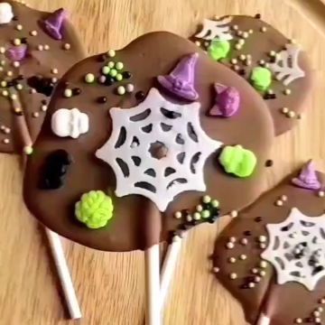 four chocolate lollipops decorated with sprinkles and decorations