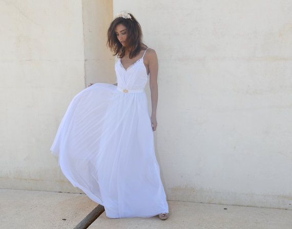 a woman in a white dress leaning against a wall