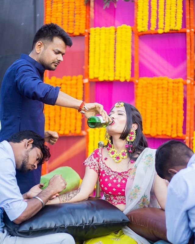 a man pours beer to a woman's face while other people sit around