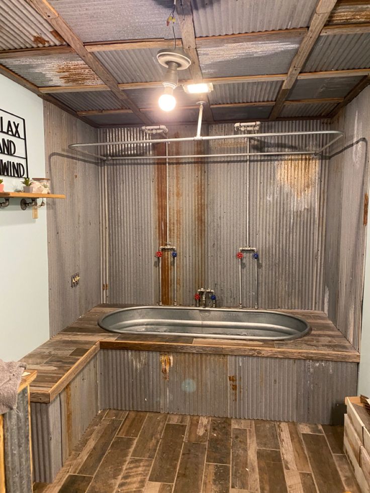 an unfinished bathroom with a metal tub and sink in the center, surrounded by wood planks