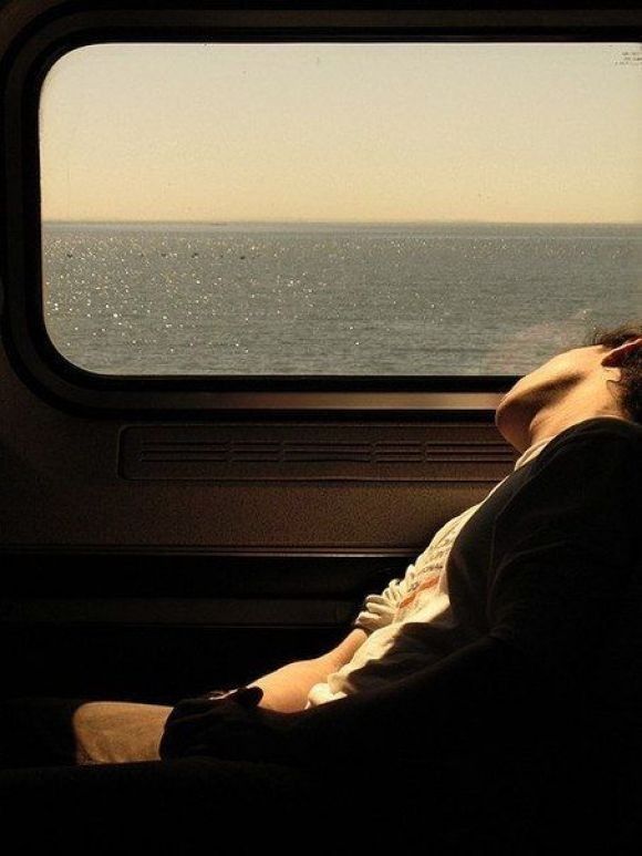 a man sleeping on a train next to the ocean