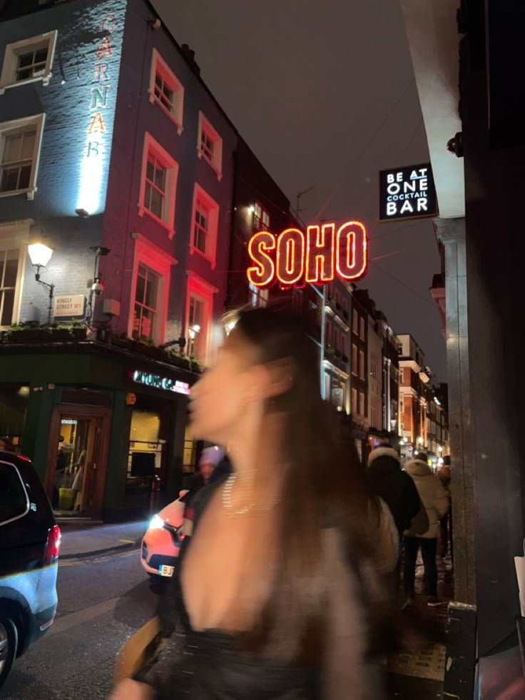 a blurry photo of people walking on the sidewalk in front of some buildings at night