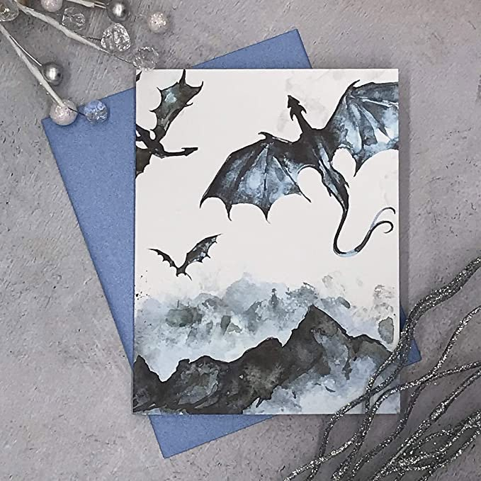 two greeting cards with black and white dragon designs on them next to some silver beads