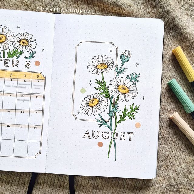 an open planner with flowers on it next to crayon markers and pencils