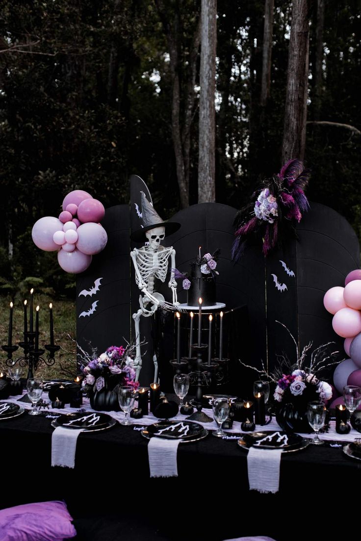 a table topped with balloons, candles and a skeleton on top of a black headboard