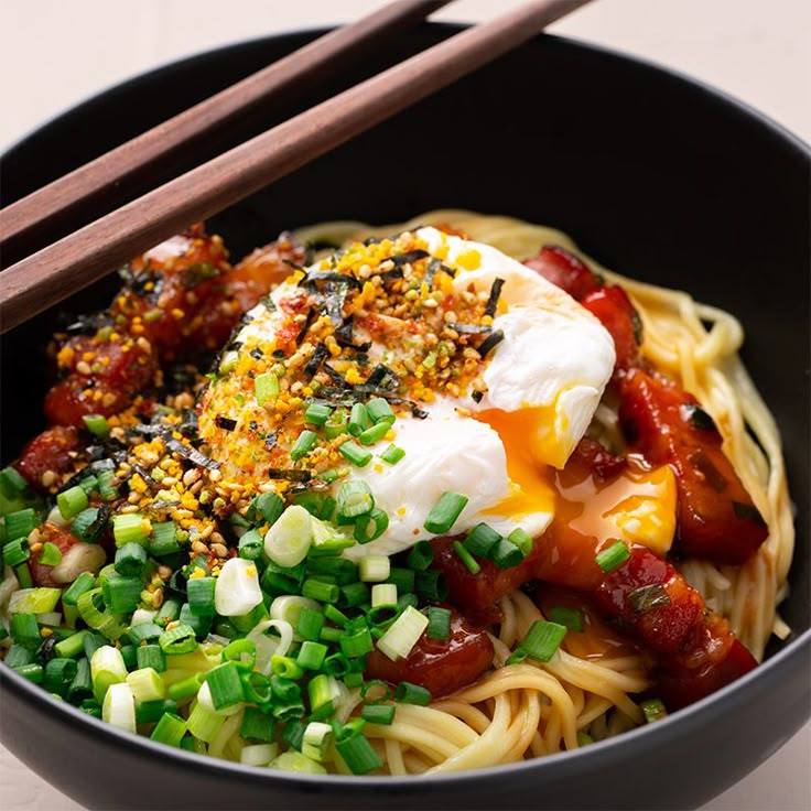 a bowl filled with noodles and vegetables next to chopsticks