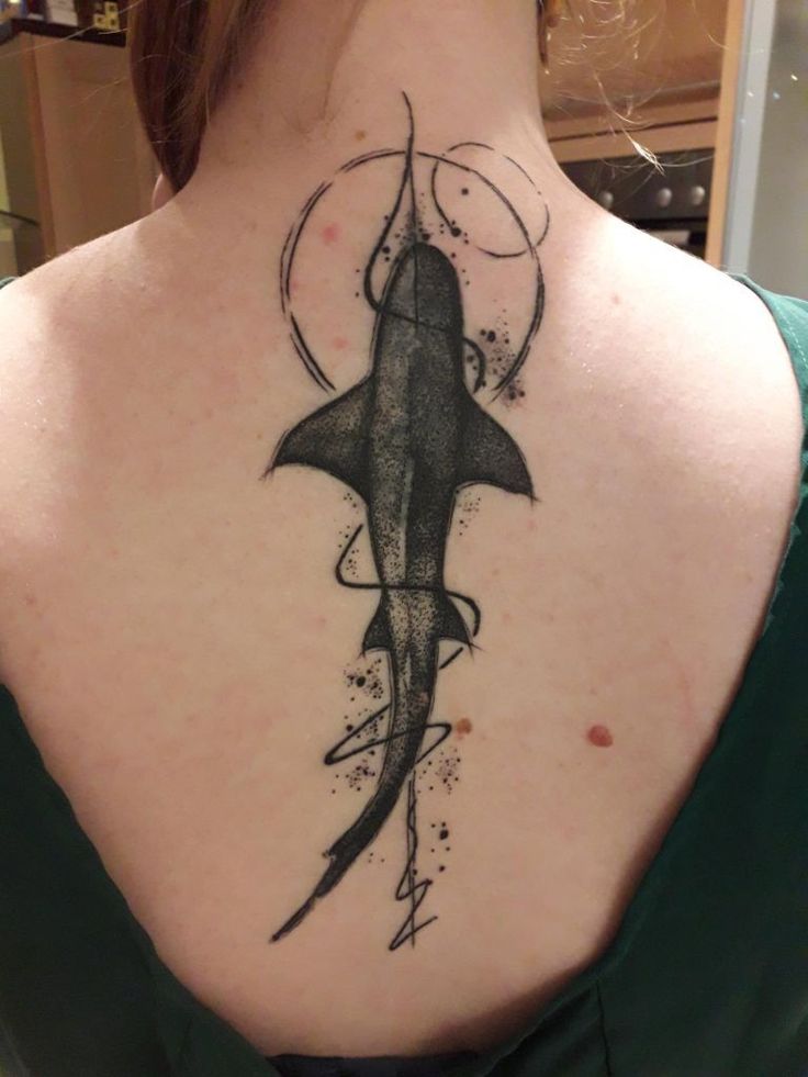 the back of a woman's neck with a shark tattoo on it