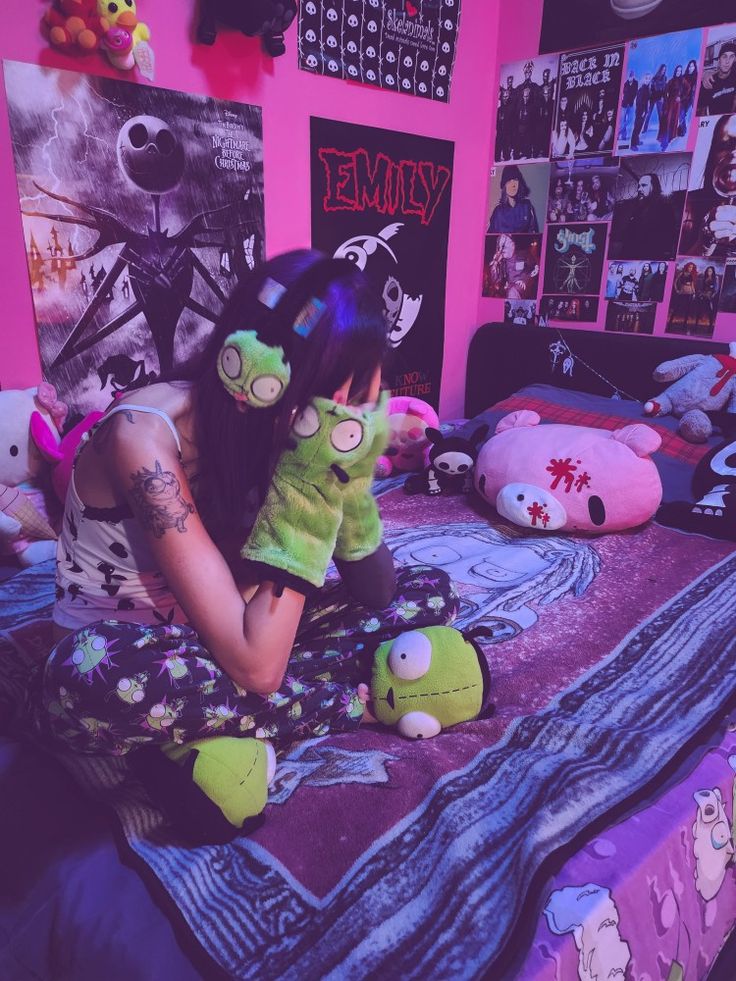 a woman sitting on top of a bed next to stuffed animals in a room with pink walls