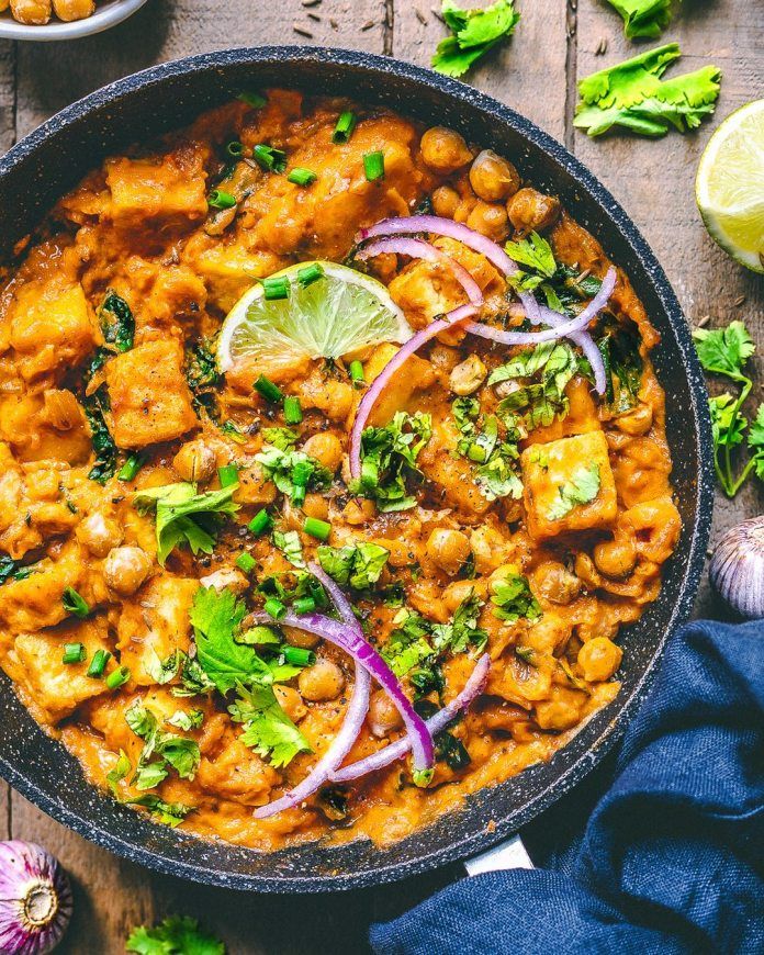 a skillet filled with food and garnished with cilantro, onions, green herbs and limes