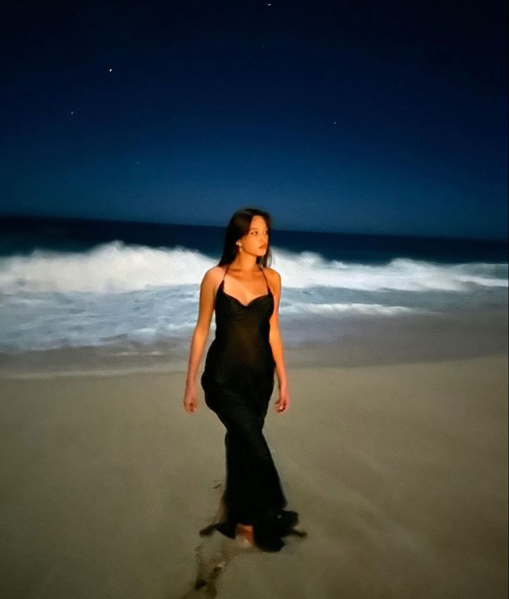 a woman is standing on the beach at night