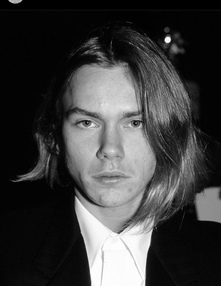 a man with long hair wearing a suit and tie