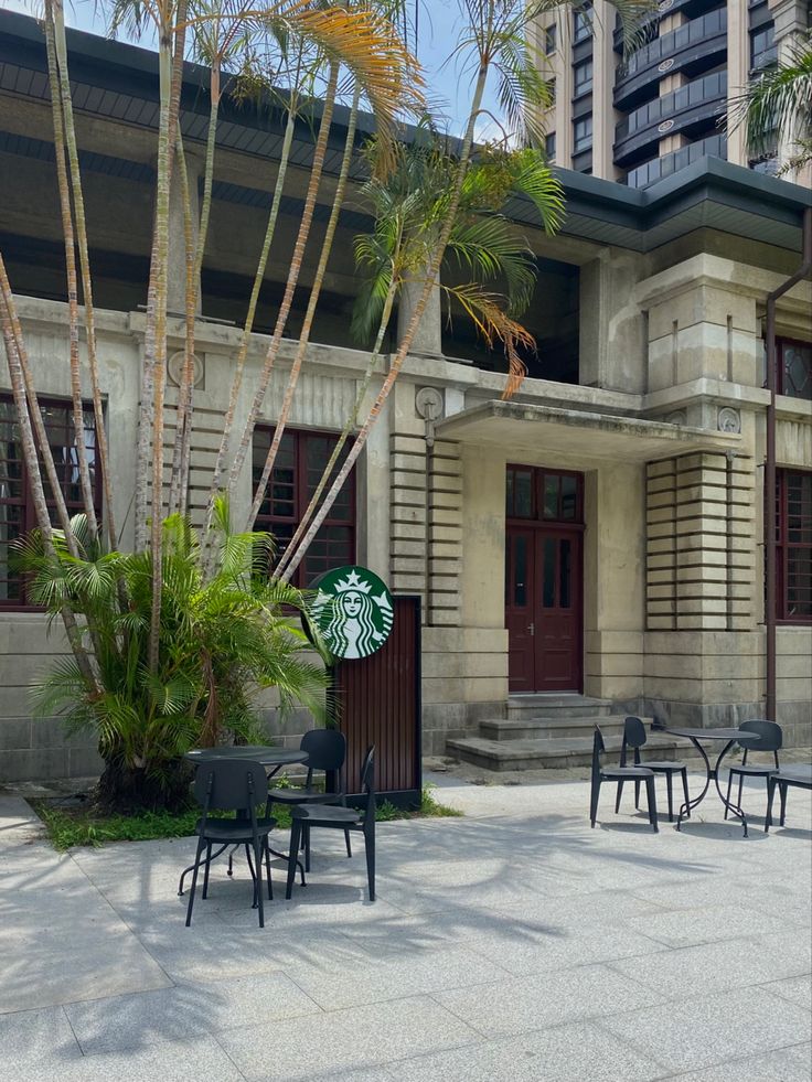 tables and chairs in front of a building with palm trees