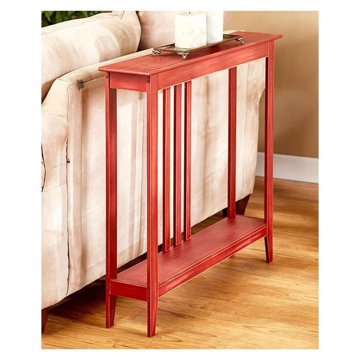 a red end table sitting on top of a wooden floor next to a white couch