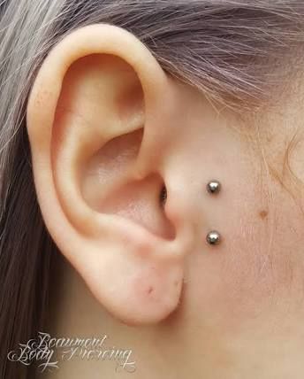 a close up of a person with a piercing on their ear and behind the ear