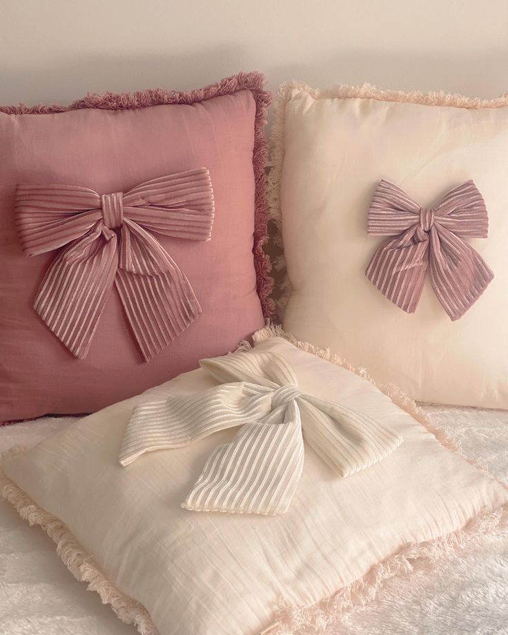 two decorative pillows with bows on them