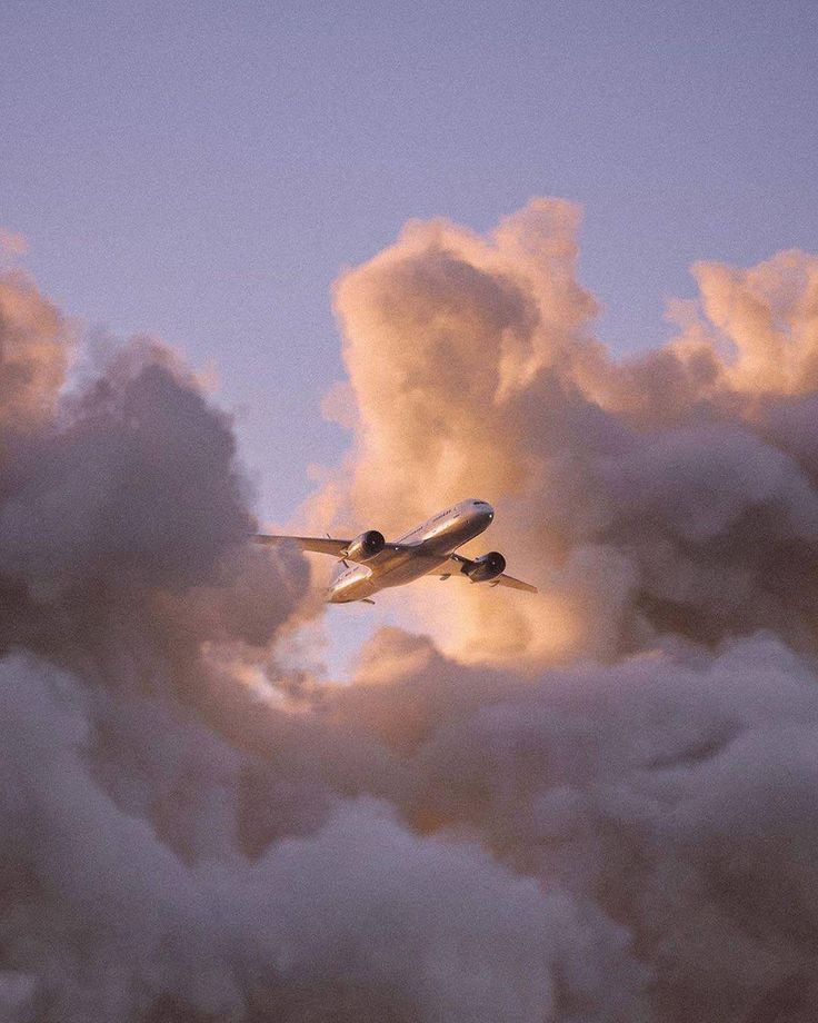 an airplane is flying through the clouds in the evening sky with it's landing gear down