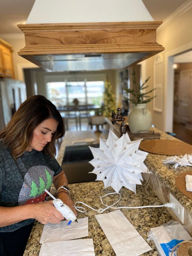 a woman is making paper snowflakes on the kitchen counter