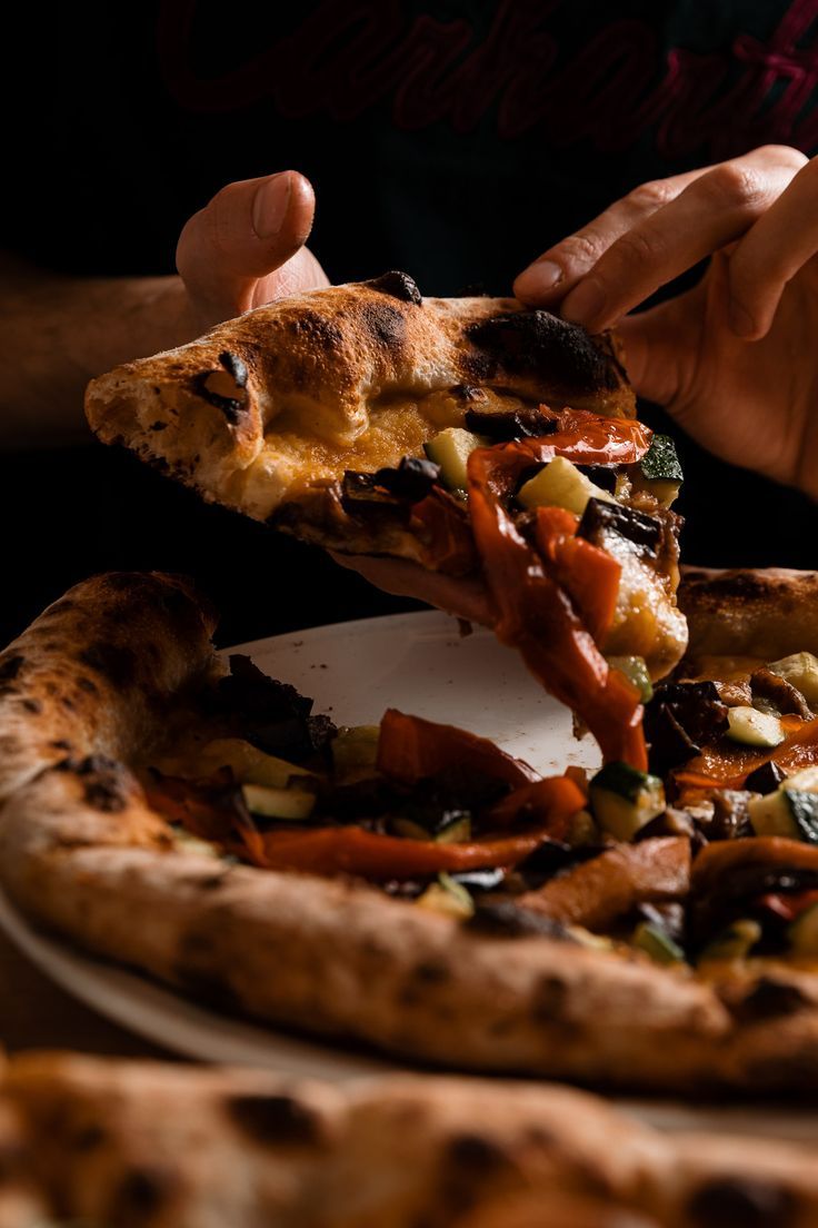 a person taking a slice of pizza from a plate