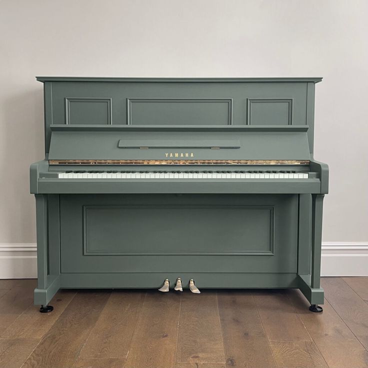 a green piano sitting on top of a hard wood floor next to a white wall