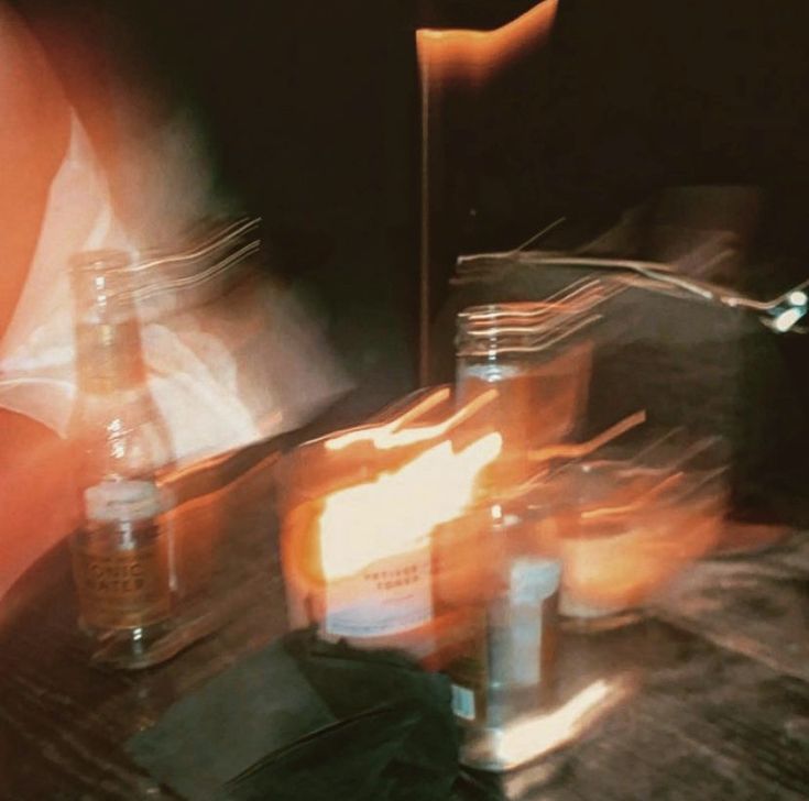 a blurry photo of bottles and candles on a table with a person in the background