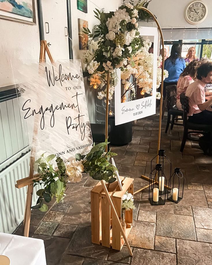 a group of people sitting at tables in a room with flowers and signs on the wall