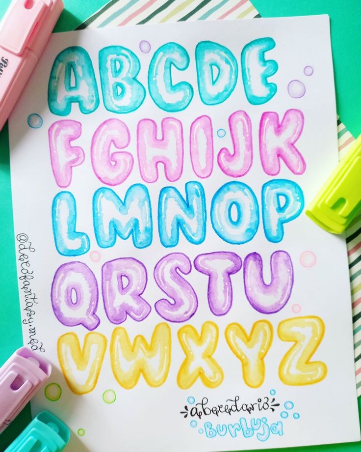 the letters and numbers are drawn with colored pencils on top of a sheet of paper