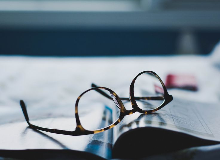 a pair of glasses sitting on top of a newspaper