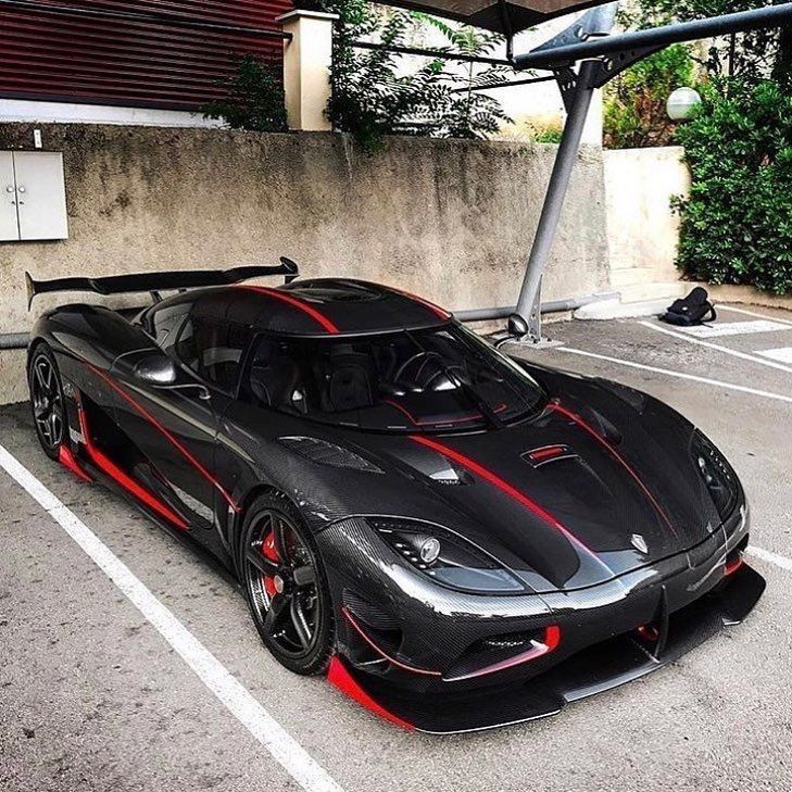 a black sports car with red stripes parked in a parking lot next to a building