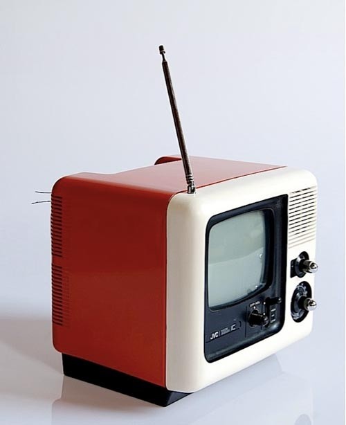 an old red and white television sitting on top of a table next to a toothbrush