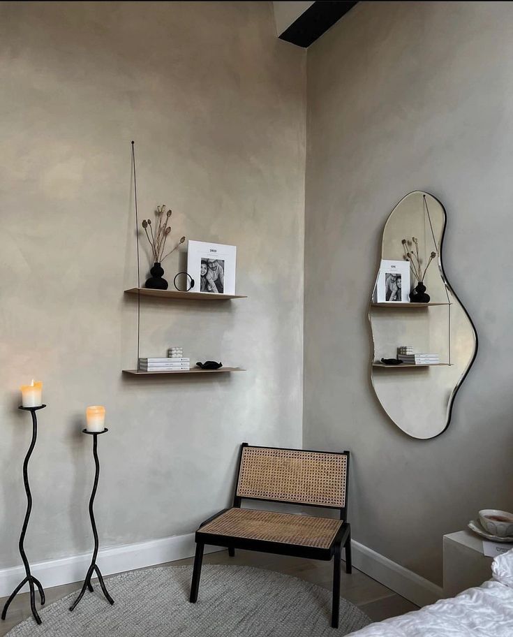 a room with two mirrors, a chair and candles on the wall in front of it