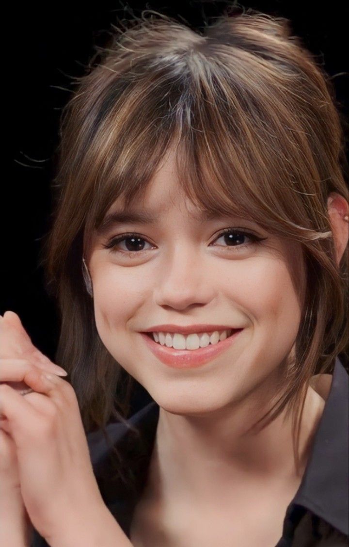 a young woman smiling and holding her hands together