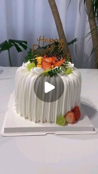 a white cake sitting on top of a table next to a palm tree and a sign that says happy birthday