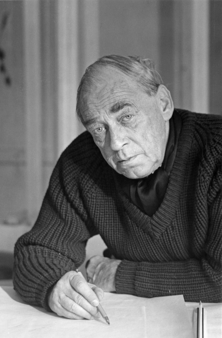 an old man sitting at a table with his hands on his knees and looking off to the side