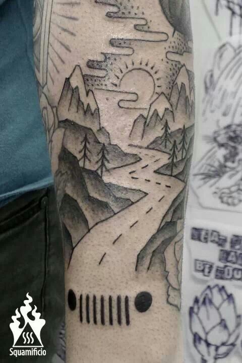 a man's arm with a landscape tattoo on it