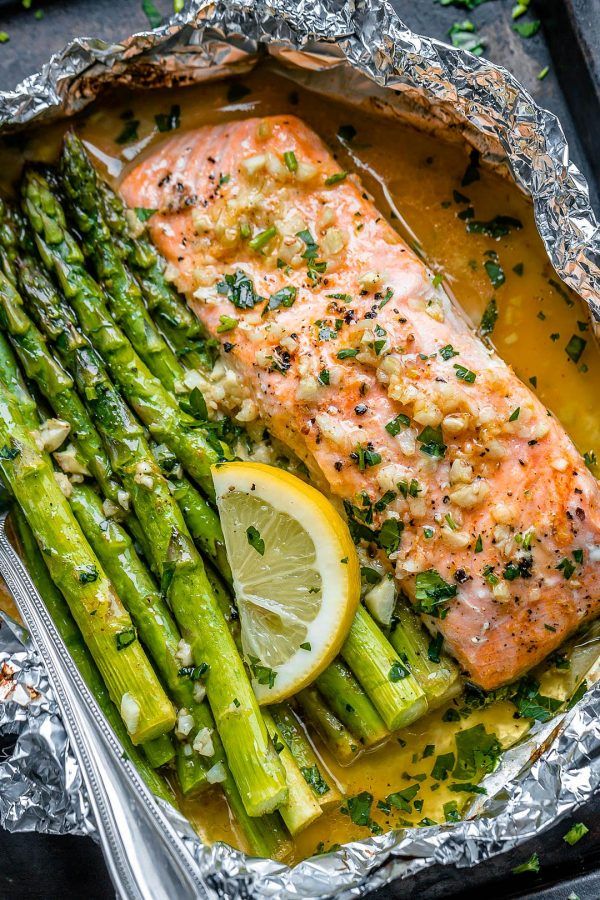 salmon and asparagus in foil with lemon wedges on the side, ready to be served