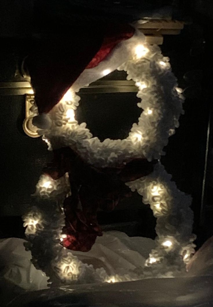 a christmas wreath with lights on it and a santa hat hanging from the front end