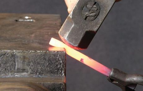 welder working on an object with red light coming out of the end of it