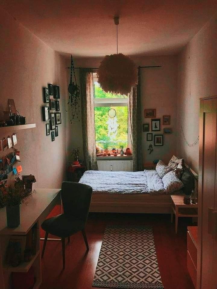 a bedroom with a bed, desk and chair next to a window in the corner