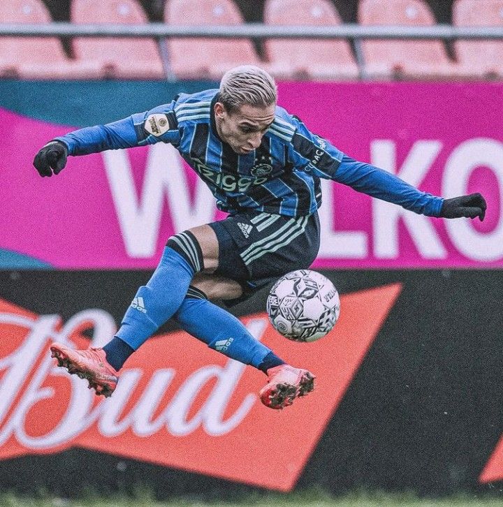 a man kicking a soccer ball on top of a field