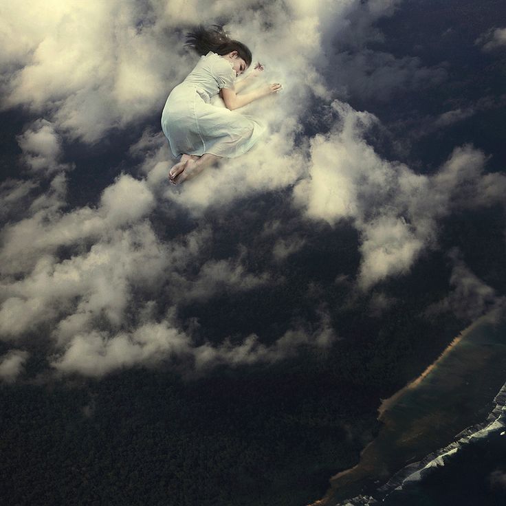 a woman flying through the air on top of clouds