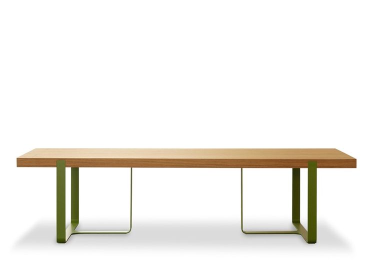 a wooden table with green metal legs and a white wall in the backround