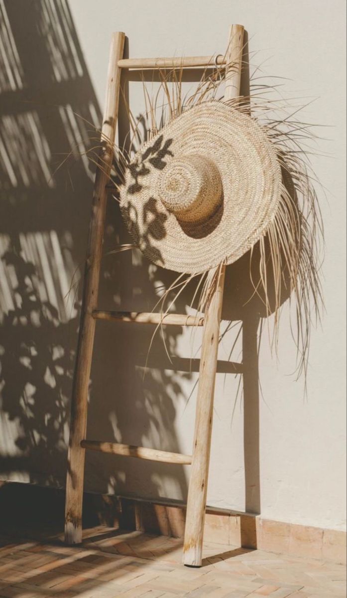 a straw hat sitting on top of a wooden ladder