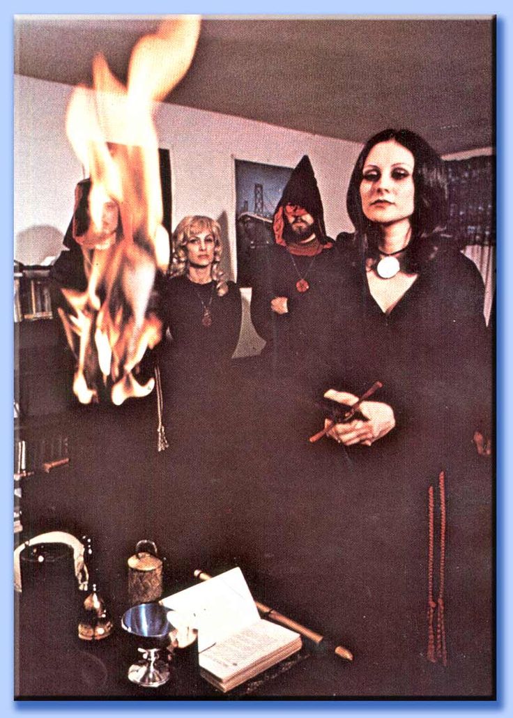 a group of people standing in a room with a fire coming out of the fireplace