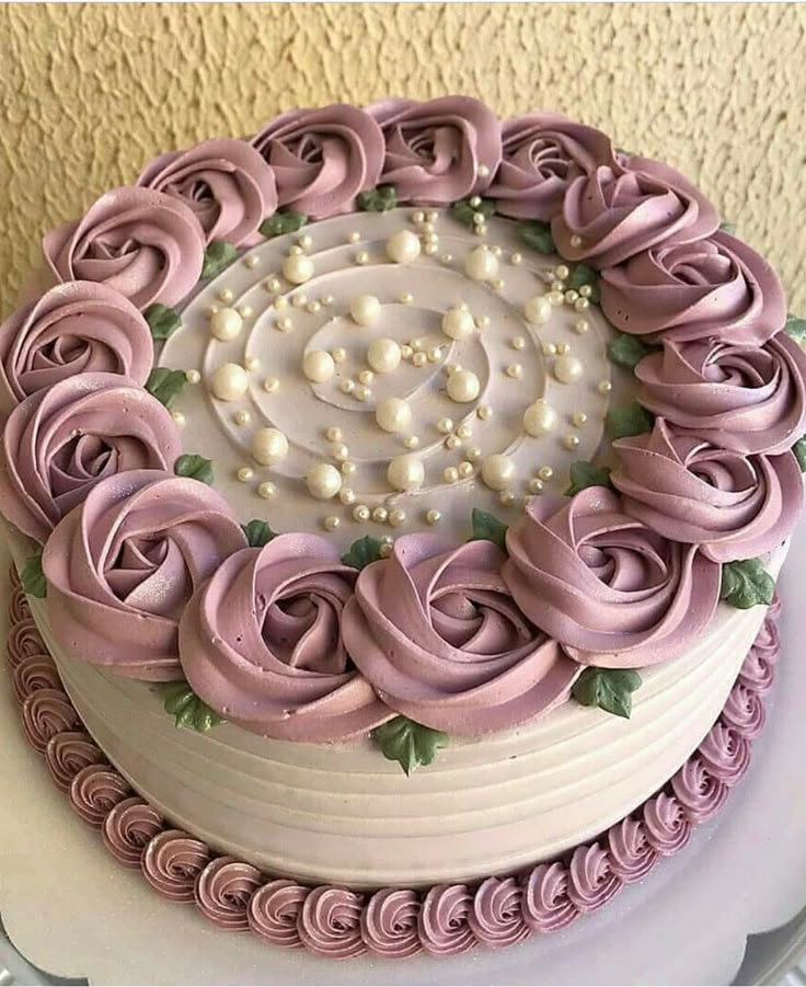 a cake decorated with pink icing and white frosting roses on top of a table