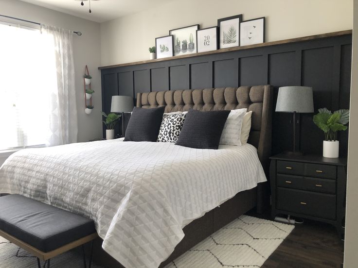 a bedroom with black and white bedding, gray headboard, and two framed pictures on the wall