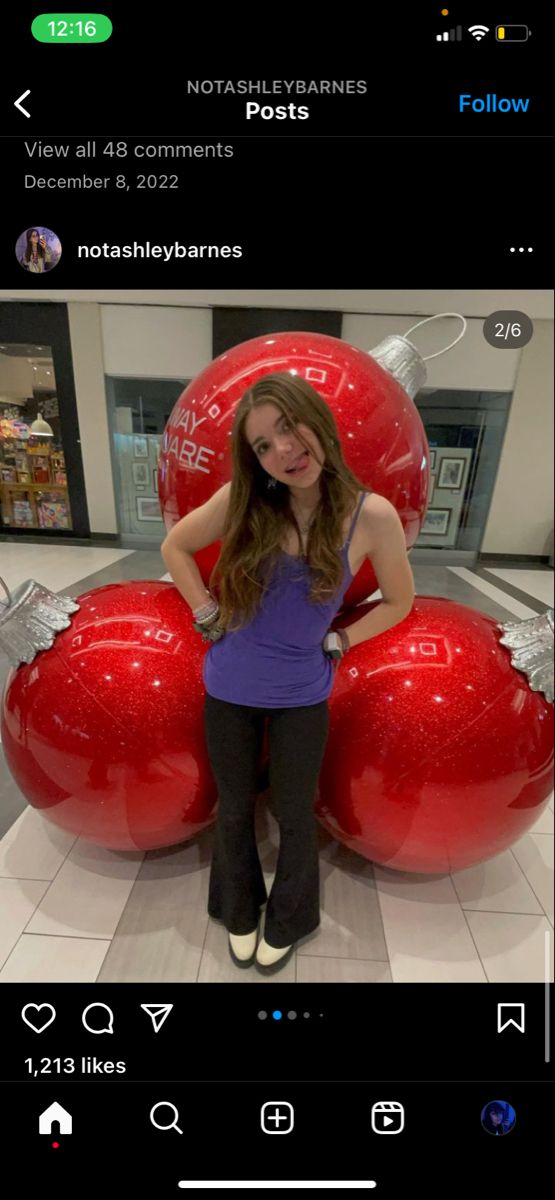 a girl standing in front of some red balls on display at the mall with her hands on her hips